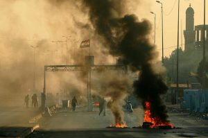 Fuerzas de seguridad iraquíes lanzan gas lacrimógeno para dispersar a manifestantes contrarios al gobierno que encendieron fuegos y cortaron una calle, durante una manifestación en Bagdad, Irak